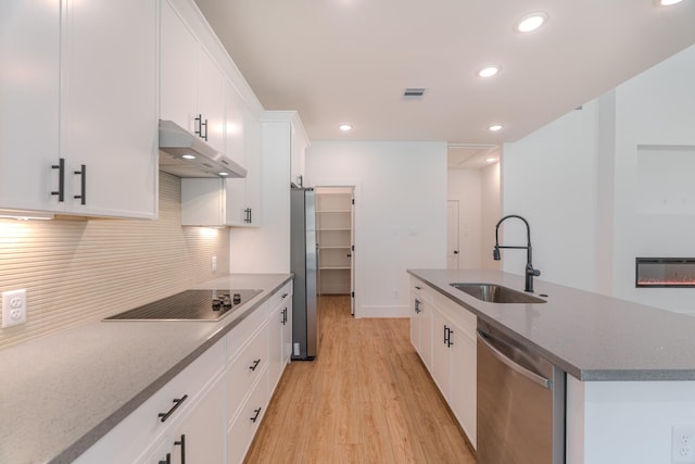3203 Hemingway Dr, Montgomery, TX 77356 - kitchen with a sink, stainless steel appliances, under cabinet range hood, light wood-type flooring, and a kitchen island with sink