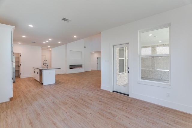 3203 Hemingway Dr, Montgomery, TX 77356 - unfurnished living room with a glass covered fireplace, light wood-type flooring, a sink, recessed lighting, and baseboards