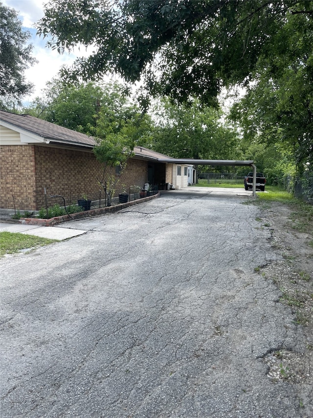 view of front of home with brick siding, driveway, and a carport
