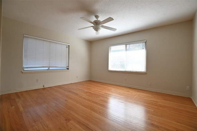 spare room with light wood finished floors, a ceiling fan, baseboards, and a textured ceiling