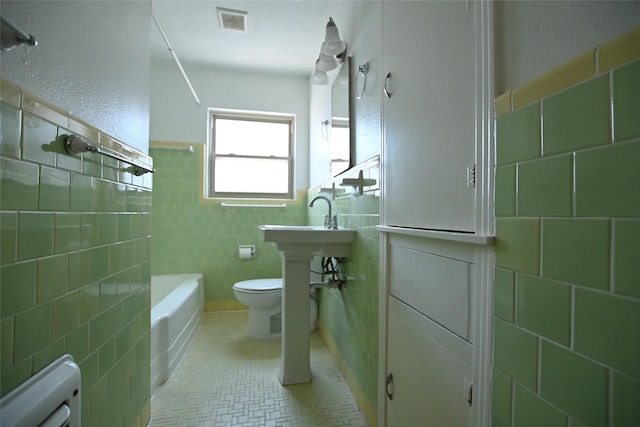 bathroom featuring toilet, tile walls, and tile patterned floors