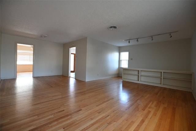 spare room with light wood-style floors, baseboards, and track lighting