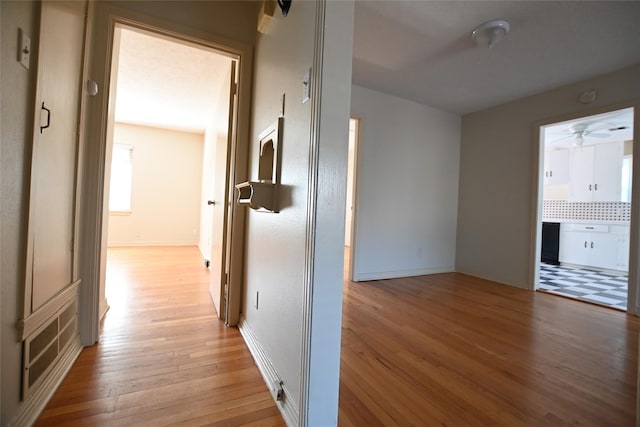 corridor featuring light wood finished floors and baseboards