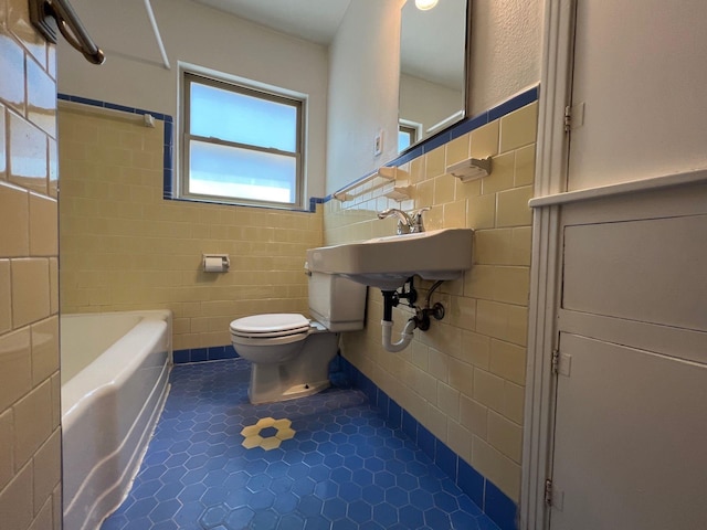 full bathroom with tile walls, tile patterned flooring, toilet, a bath, and a sink