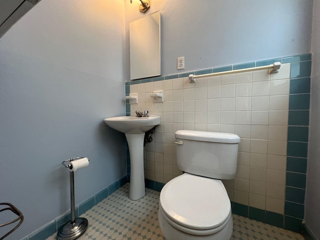 bathroom with toilet, tile walls, and tile patterned floors