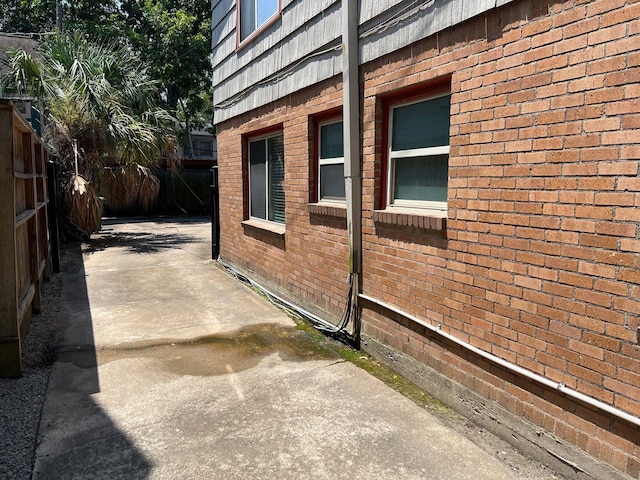 view of side of property with fence, brick siding, and a patio area