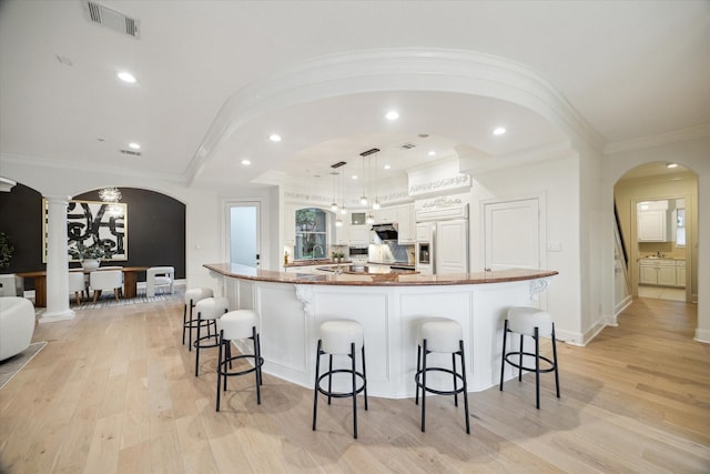 22 Berenger Pl, Sugar Land, TX 77479 - kitchen with paneled built in fridge, arched walkways, a kitchen bar, ornamental molding, and light wood-type flooring