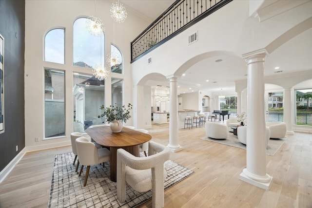 22 Berenger Pl, Sugar Land, TX 77479 - dining room with decorative columns, arched walkways, light wood-style floors, crown molding, and a high ceiling