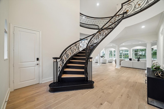 22 Berenger Pl, Sugar Land, TX 77479 - entrance foyer with ornate columns, a towering ceiling, stairs, arched walkways, and light wood-type flooring