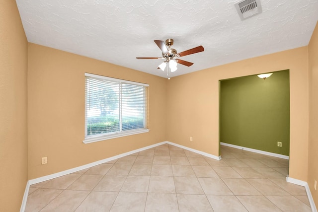 spare room featuring ceiling fan, light tile patterned floors, baseboards, and a textured ceiling
