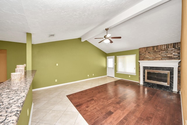 unfurnished living room featuring ceiling fan, a high end fireplace, tile patterned floors, a textured ceiling, and baseboards