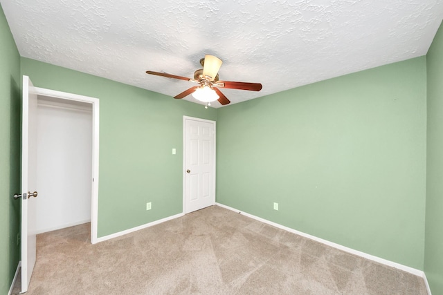 unfurnished bedroom with baseboards, carpet, a ceiling fan, and a textured ceiling