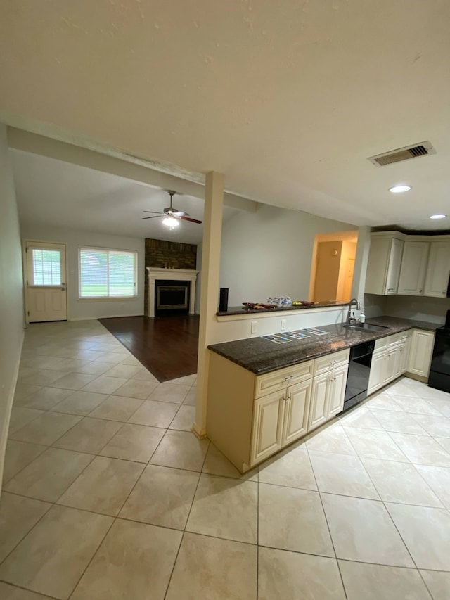 13430 Firebrick Dr, Houston, TX 77041 - kitchen featuring black dishwasher, light tile patterned flooring, dark stone countertops, open floor plan, and a large fireplace