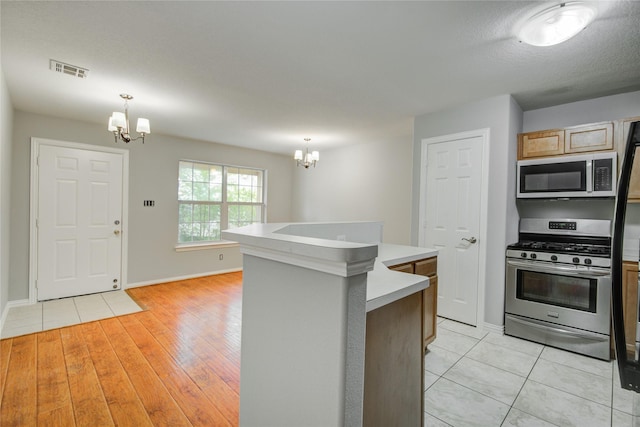 12409 Urban Dale Ct, Houston, TX 77082 - kitchen featuring stainless steel appliances, a chandelier, light countertops, a kitchen island, and baseboards