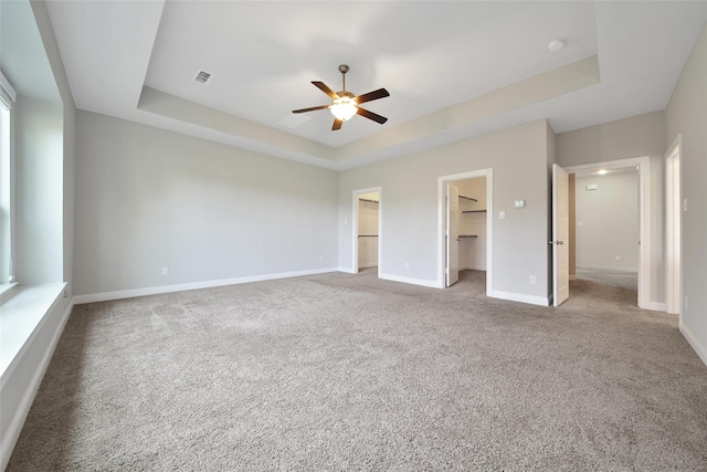 18323 Parkview Point Dr, Houston, TX 77094 - unfurnished bedroom with a tray ceiling, carpet flooring, a walk in closet, baseboards, and a ceiling fan