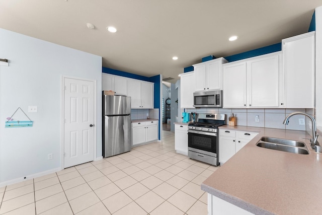 kitchen featuring stainless steel appliances, a sink, backsplash, white cabinetry, and recessed lighting