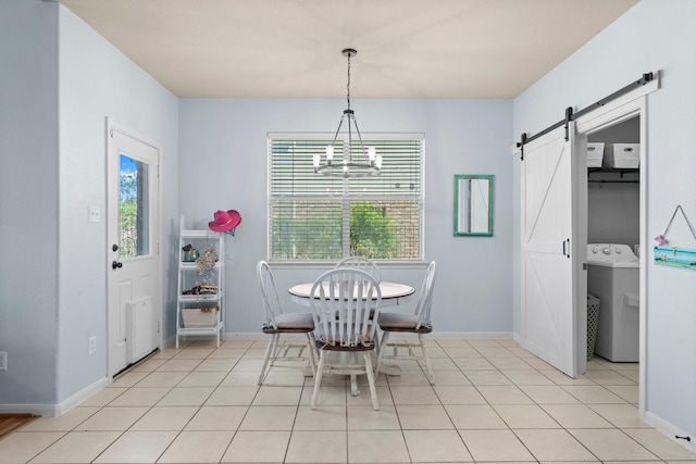dining room featuring washer / dryer, a chandelier, baseboards, a barn door, and light tile patterned flooring