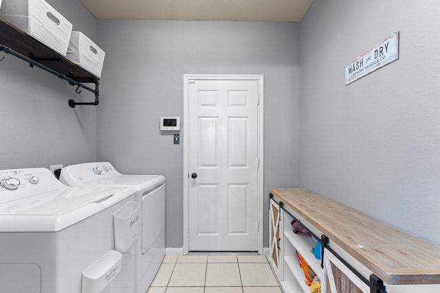 washroom with washing machine and dryer, light tile patterned floors, and baseboards