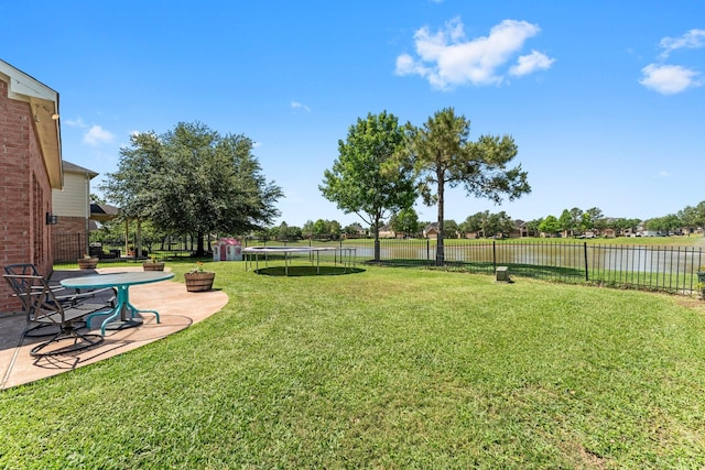 view of yard with a trampoline, a patio area, and a water view