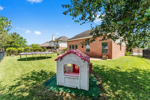 rear view of property with a trampoline and brick siding