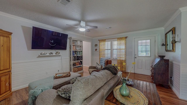 129 County Road 2063, Hull, TX 77564 - living room featuring wood finished floors, a textured ceiling, a ceiling fan, crown molding, and a wainscoted wall