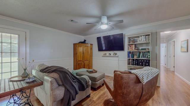 129 County Road 2063, Hull, TX 77564 - living room featuring wood finished floors, ornamental molding, a ceiling fan, a textured ceiling, and a wainscoted wall