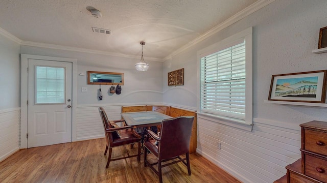 129 County Road 2063, Hull, TX 77564 - dining area with wainscoting, light wood-style floors, crown molding, a textured ceiling, and wood walls