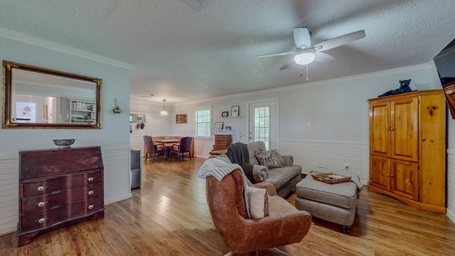 129 County Road 2063, Hull, TX 77564 - living area featuring wood finished floors, ceiling fan, a textured ceiling, crown molding, and wainscoting