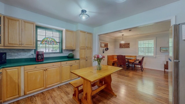 129 County Road 2063, Hull, TX 77564 - kitchen featuring freestanding refrigerator, light wood-style floors, black microwave, backsplash, and a wainscoted wall