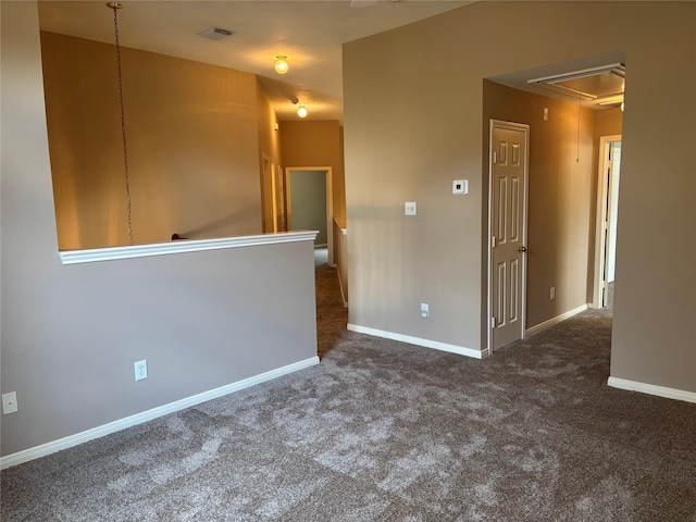 empty room with attic access, carpet flooring, and baseboards
