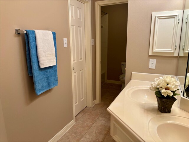 full bath featuring double vanity, tile patterned floors, a shower, baseboards, and toilet