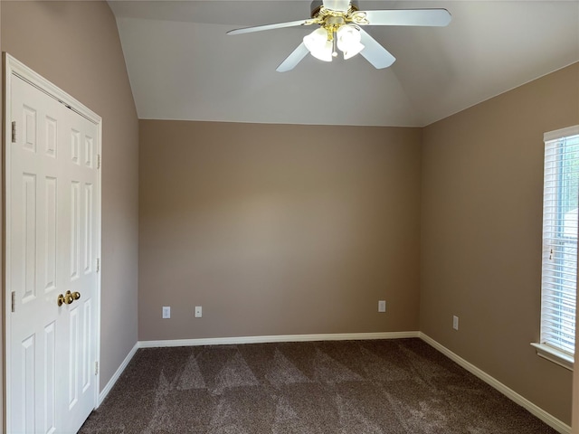 unfurnished room with lofted ceiling, dark carpet, a ceiling fan, and baseboards