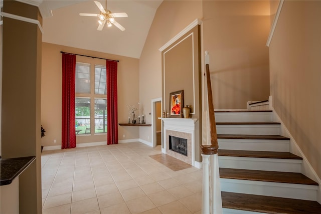 stairway featuring high vaulted ceiling, ceiling fan, tile patterned flooring, a fireplace with flush hearth, and baseboards