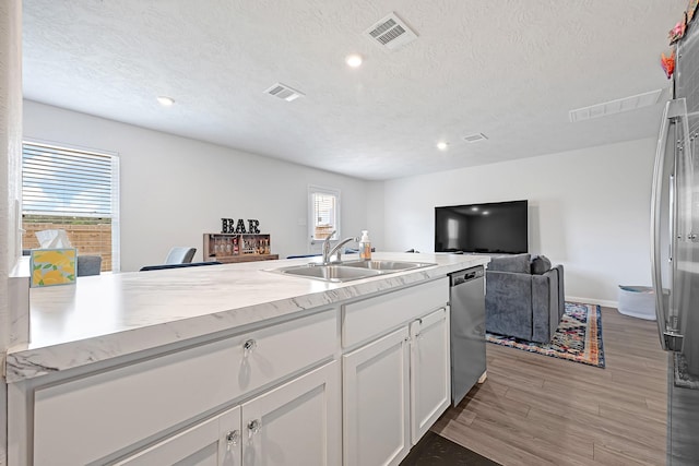 1325 Rd 5102, Cleveland, TX 77327 - kitchen featuring a sink, stainless steel dishwasher, wood finished floors, white cabinetry, and light countertops