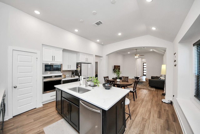 kitchen with appliances with stainless steel finishes, a sink, vaulted ceiling, ceiling fan, and arched walkways