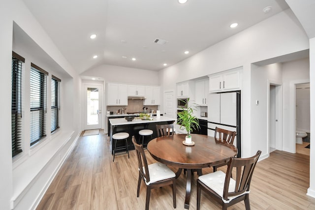 dining area featuring light wood-style flooring, recessed lighting, lofted ceiling, and baseboards