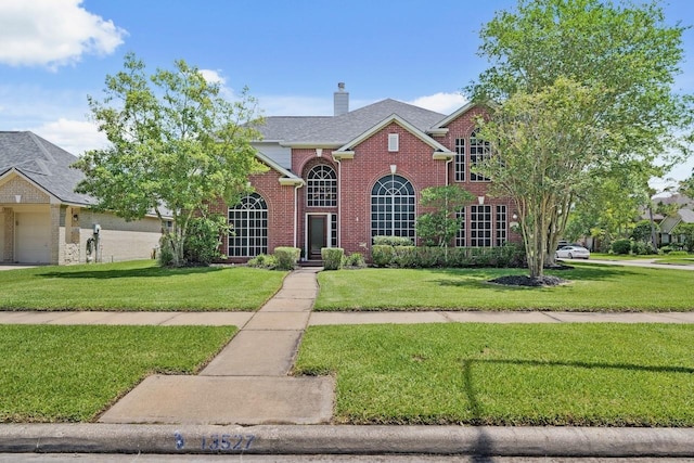 view of front of home featuring a front yard, brick siding, a chimney, and a garage