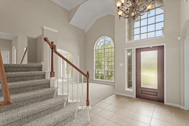 carpeted foyer with a towering ceiling, stairway, tile patterned flooring, a chandelier, and baseboards