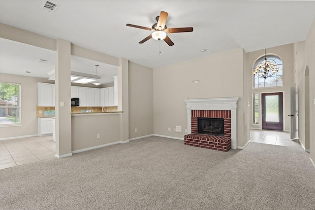 unfurnished living room featuring light carpet, a fireplace, ceiling fan, light tile patterned floors, and baseboards