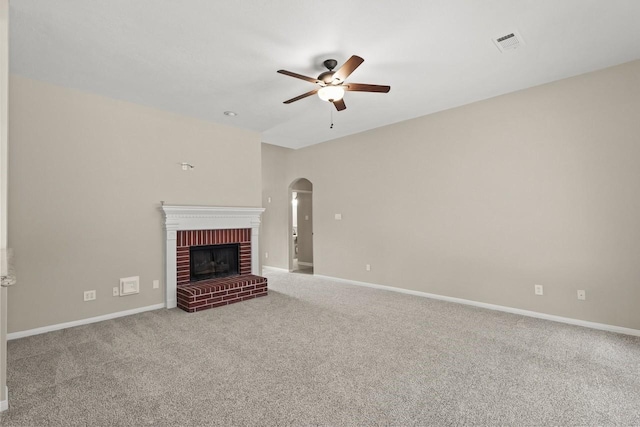unfurnished living room with ceiling fan, arched walkways, a fireplace, carpet flooring, and baseboards