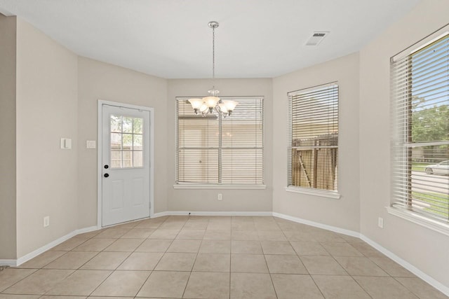 unfurnished dining area featuring a chandelier, healthy amount of natural light, light tile patterned floors, and baseboards