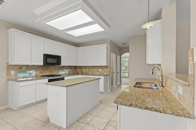 kitchen with a sink, black microwave, tasteful backsplash, light stone counters, and light tile patterned floors