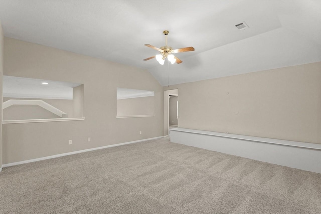 carpeted empty room with a ceiling fan, vaulted ceiling, and baseboards