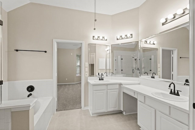 bathroom with tile patterned floors, a shower stall, a garden tub, double vanity, and vaulted ceiling