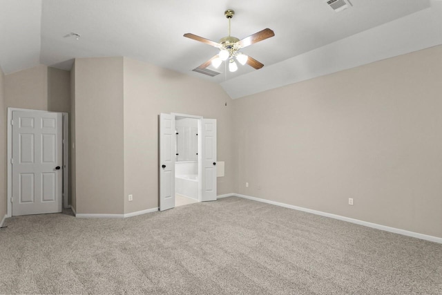 unfurnished bedroom featuring vaulted ceiling, carpet floors, baseboards, ensuite bath, and ceiling fan