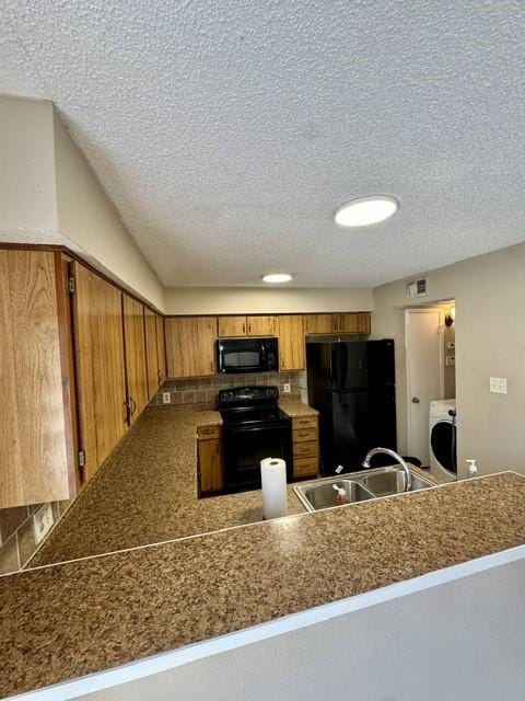 11957 Bob White Dr Unit 863, Houston, TX 77035 - kitchen with black appliances, a sink, brown cabinetry, a textured ceiling, and a peninsula
