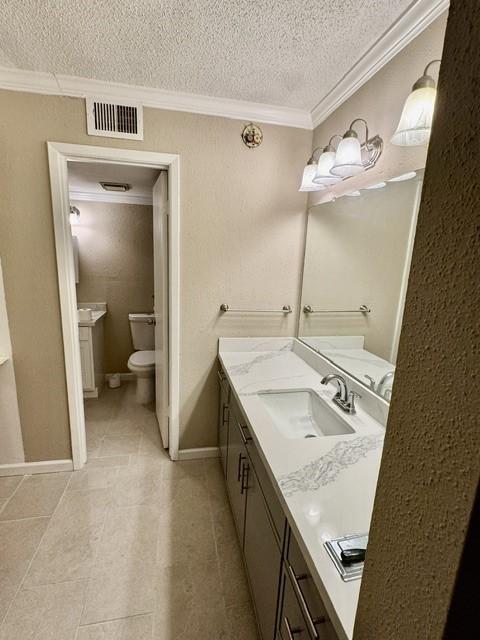 11957 Bob White Dr Unit 863, Houston, TX 77035 - bathroom featuring a textured ceiling, ornamental molding, vanity, toilet, and tile patterned flooring