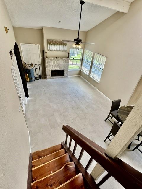 11957 Bob White Dr Unit 863, Houston, TX 77035 - stairs with ceiling fan, a textured ceiling, a fireplace, and baseboards