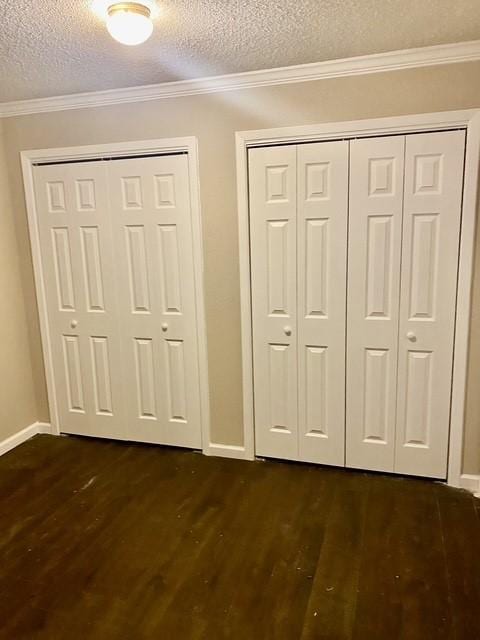 11957 Bob White Dr Unit 863, Houston, TX 77035 - unfurnished bedroom featuring dark wood finished floors, a textured ceiling, baseboards, ornamental molding, and multiple closets
