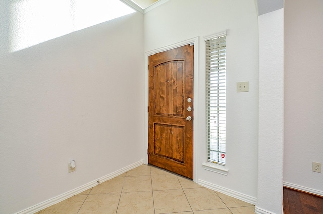 foyer entrance featuring light tile patterned flooring, plenty of natural light, and baseboards
